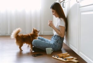 Young woman sitting with pet on kitchen floor